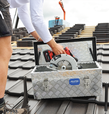 Dachdecker verstaut Handkreissäge in ALUTEC EXTREME Alu-Riffelblechbox