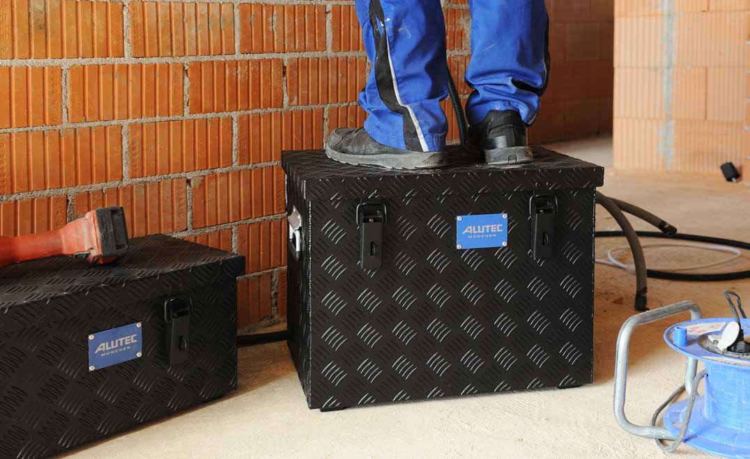 Person steht auf ALUTEC EXTREME Alu-Riffelblechbox bei Installationsarbeiten in Rohbau
