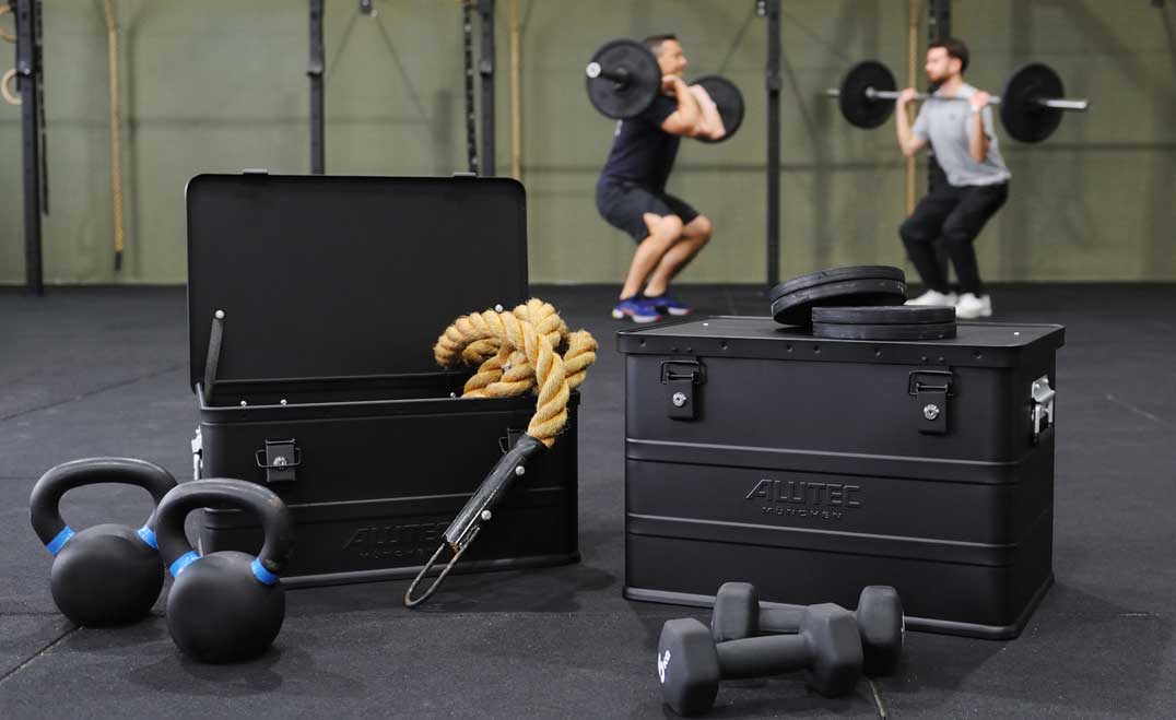 Trimmgeräte mit ALUTEC CLASSIC BLACK Aluboxen im Kraftraum mit Sportler